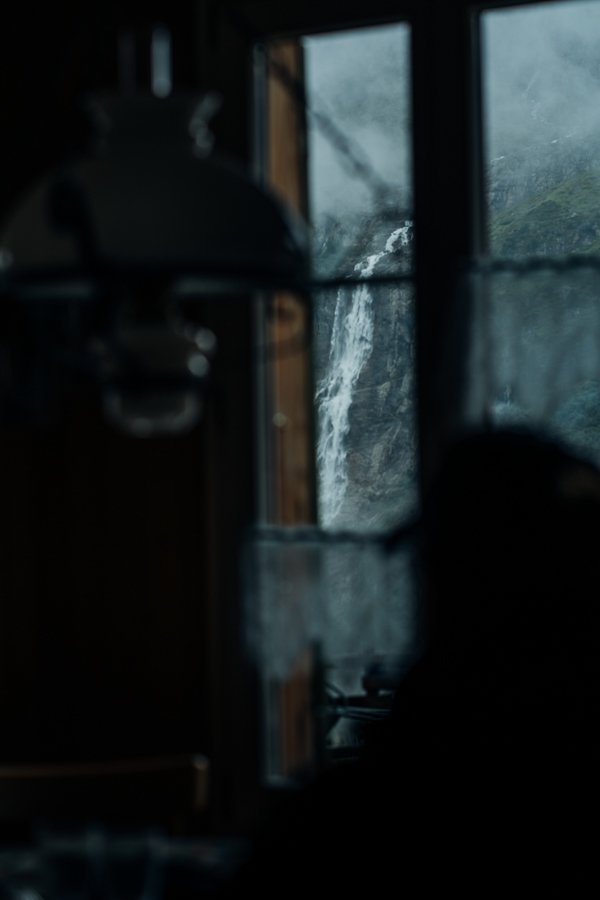 Eine Person, die aus einem Fenster auf einen Wasserfall blickt.