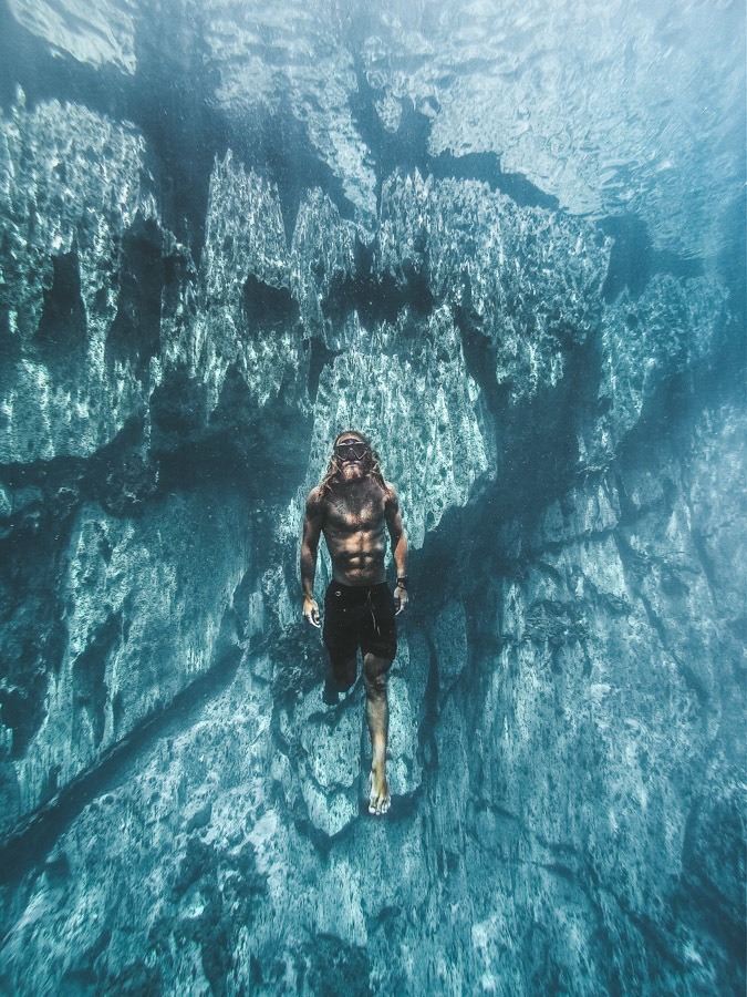 Ein Mann schwimmt im Wasser in der Nähe von Felsen.