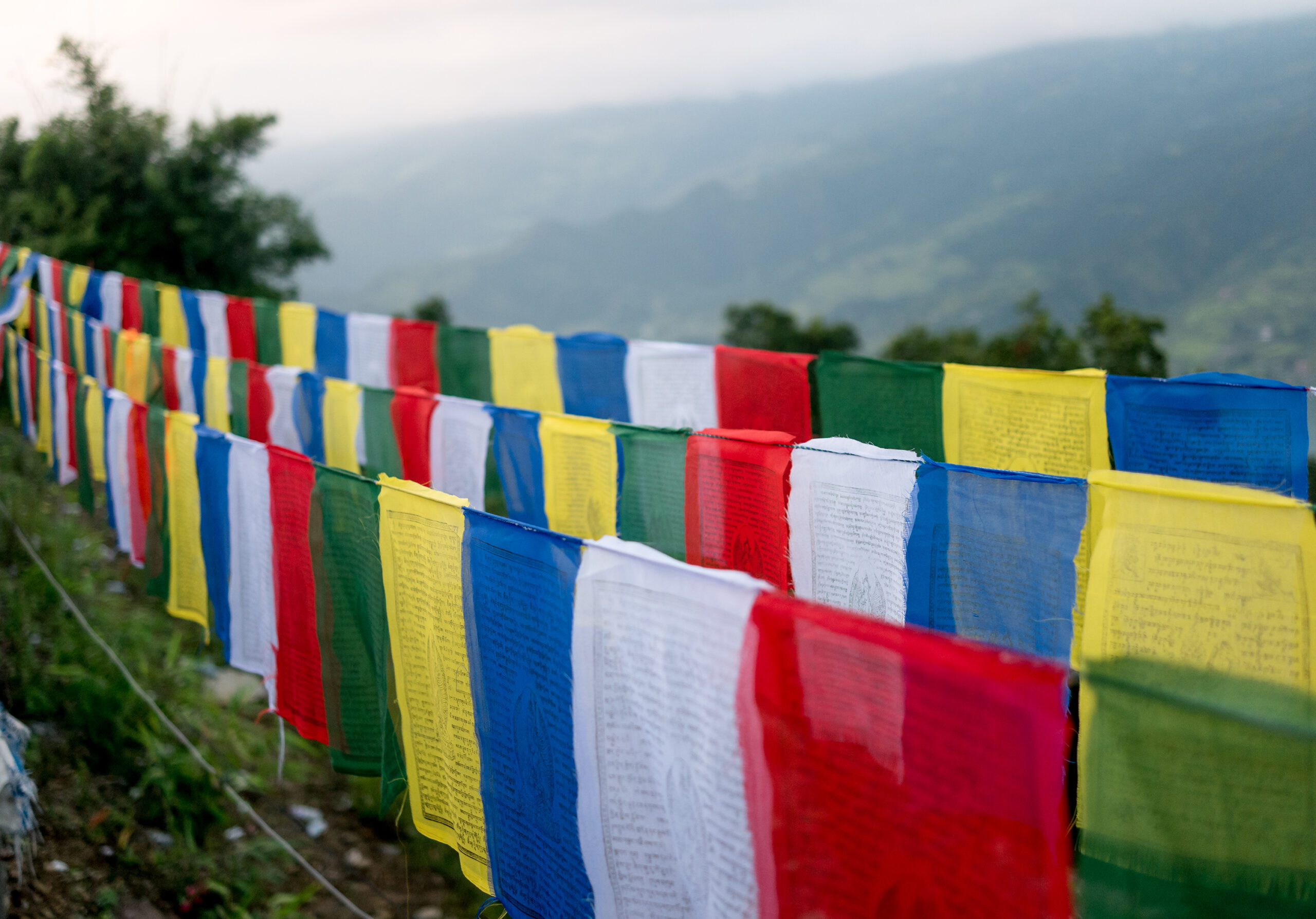 Eine Reihe bunter Gebetsfahnen auf einem Hügel, die Frieden und Spiritualität entlang der Strecke von Kathmandu nach Pokhara symbolisieren.